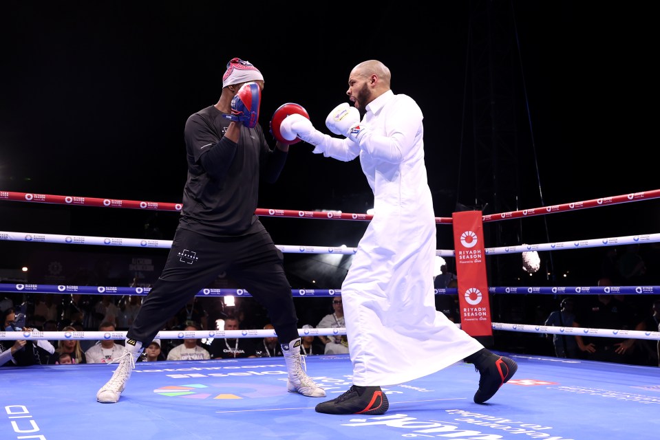 a man in a white robe is walking out of a boxing ring .