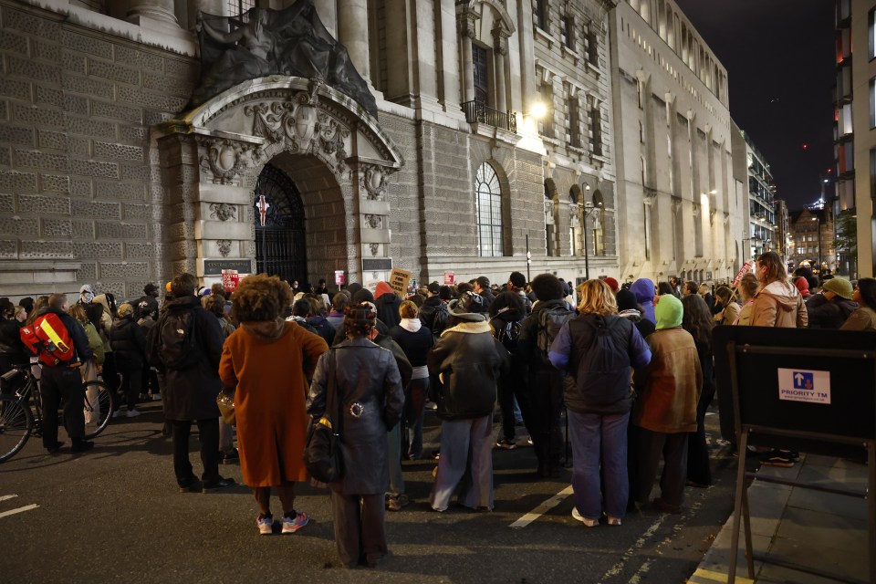 a group of people are gathered outside of a building with a sign that says emergency exit