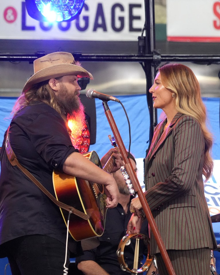 a man playing a guitar and a woman singing in front of a sign that says luggage