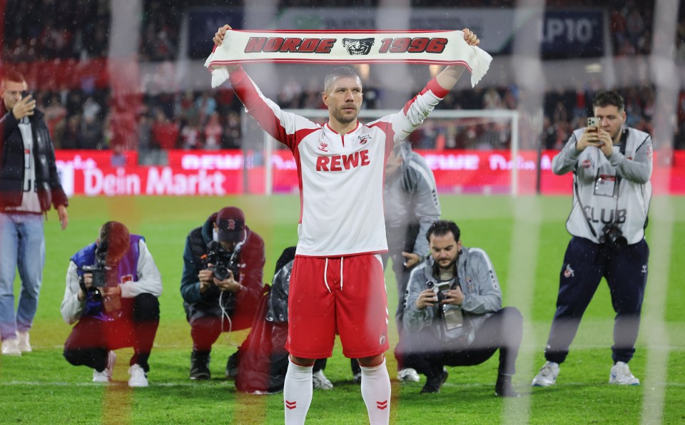 a man in a rewe jersey holds up a scarf