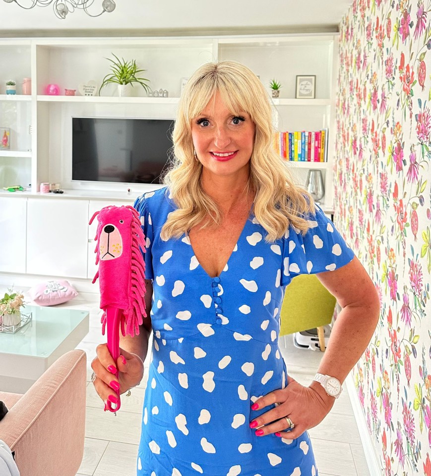 a woman in a blue and white polka dot dress holds a pink dog mop