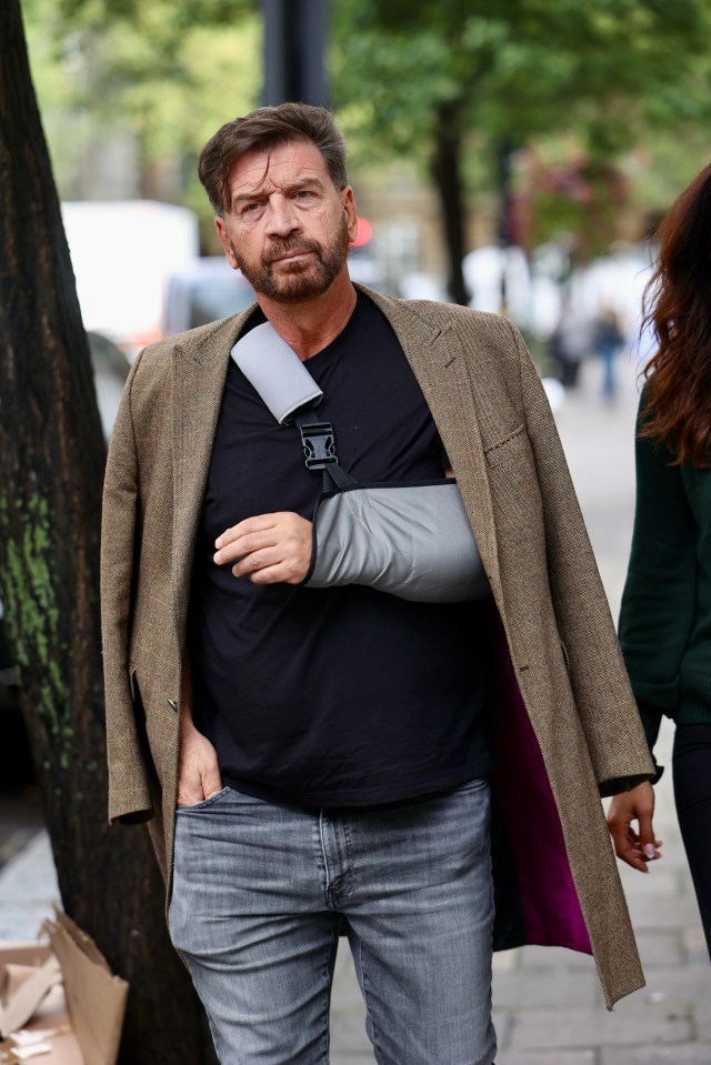 a man with a cast on his arm is walking down the street