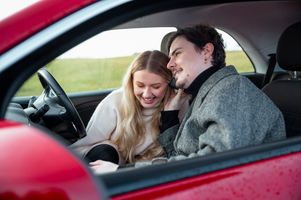 a man and a woman are sitting in a red car