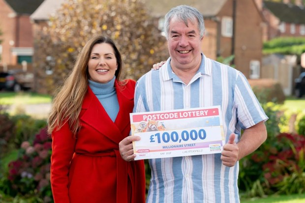 a man and woman holding a postcode lottery cheque