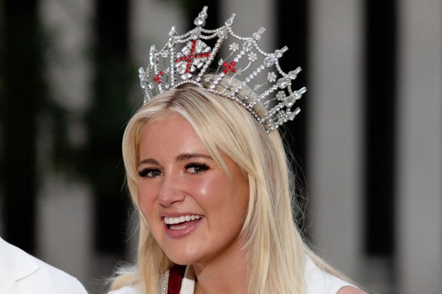 a woman wearing a miss england sash stands next to a man