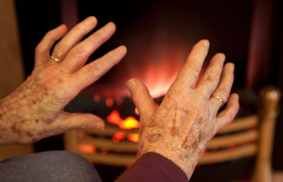 a person 's hands are reaching out towards a fireplace