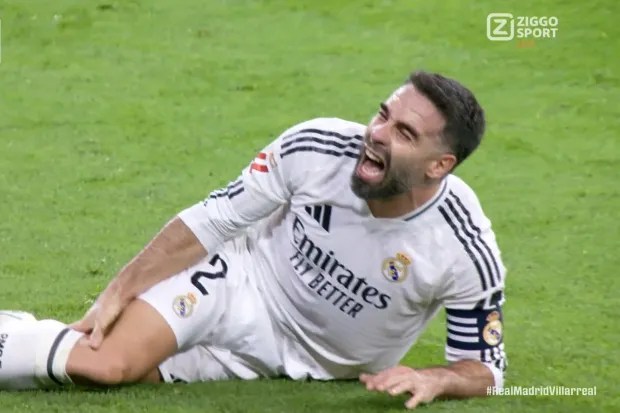 a soccer player is laying on the ground with his mouth open .