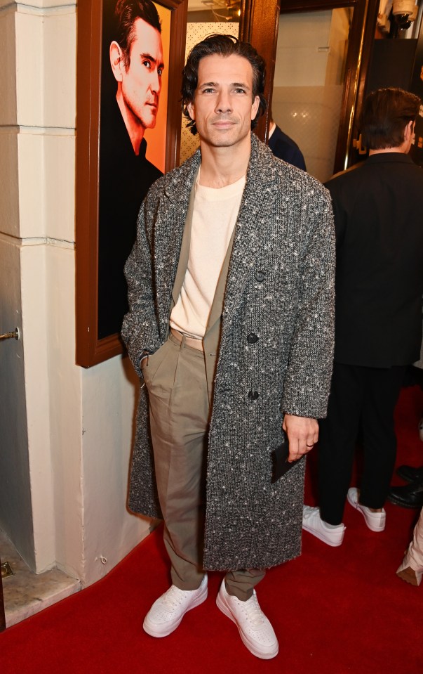 a man standing on a red carpet with his hands in his pockets