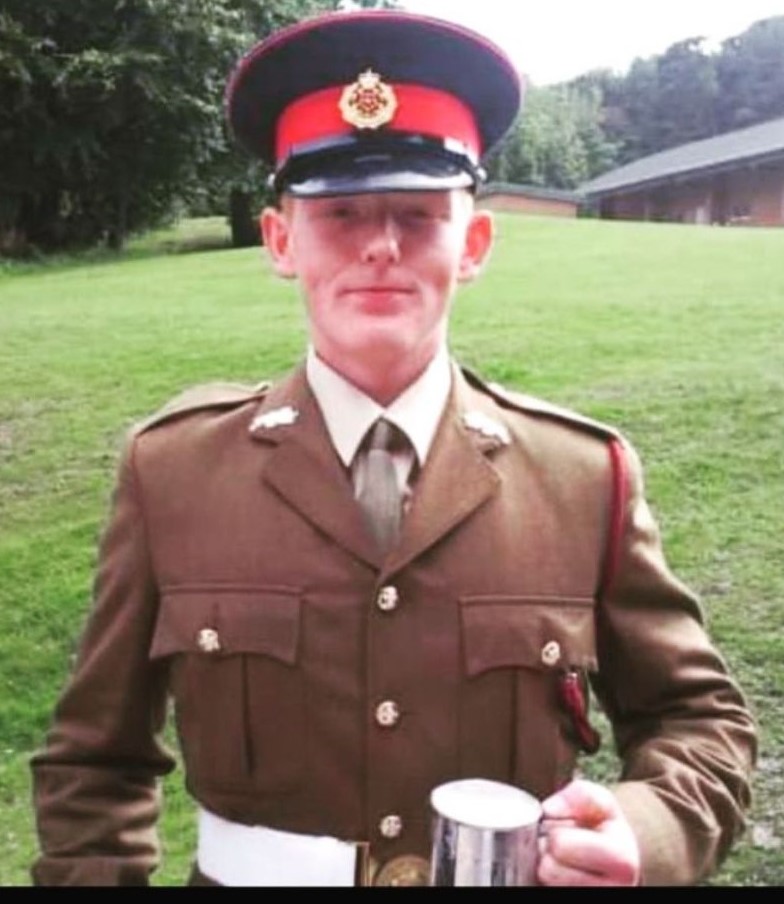 a man in a military uniform is holding a cup .