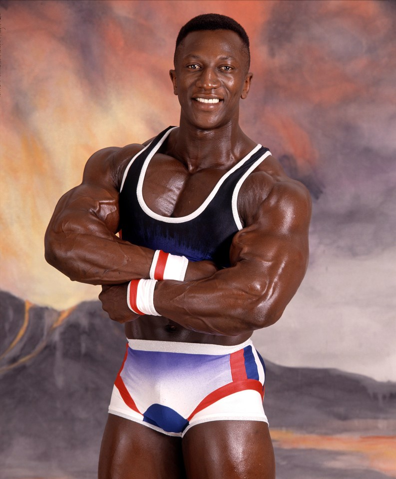 a man in a tank top and shorts is smiling with his arms crossed