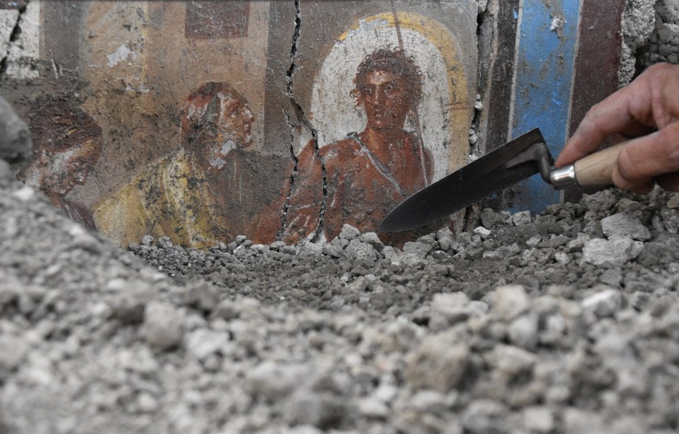 a person holding a shovel in front of a painting on a wall