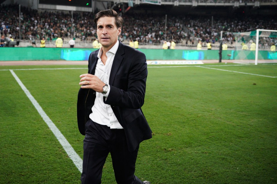 a man in a suit walks on a soccer field