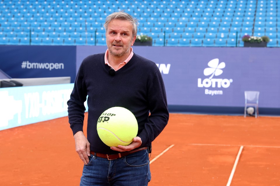 a man holding a tennis ball in front of a sign that says lotto bayern