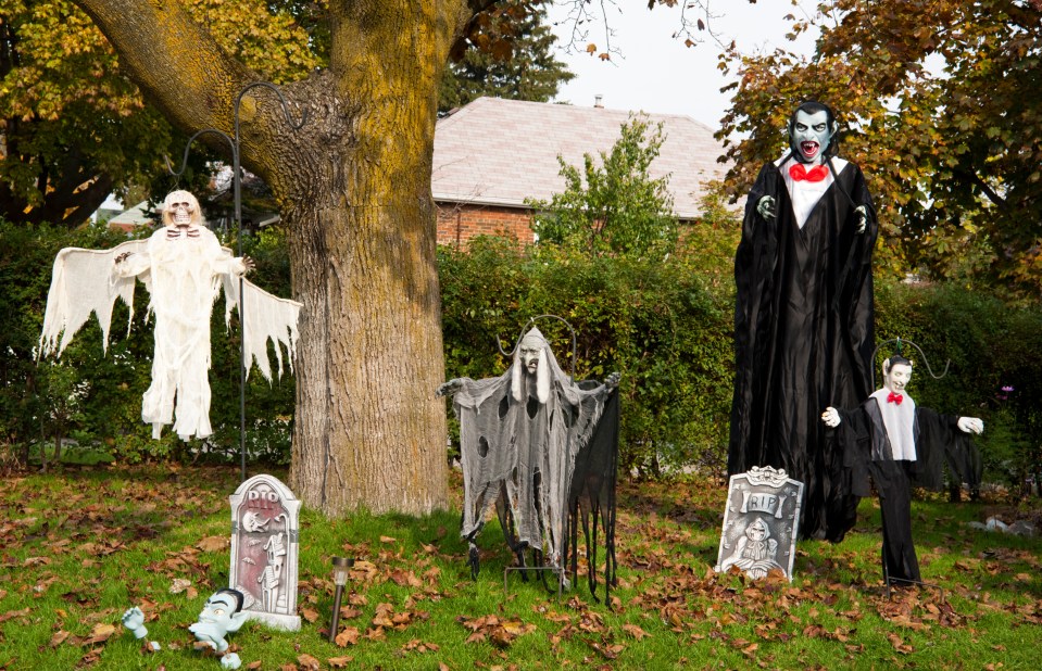 halloween decorations in front of a tree including a vampire and a ghost