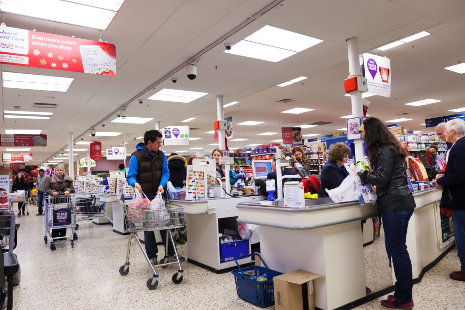 a tesco sign hangs above the checkout line