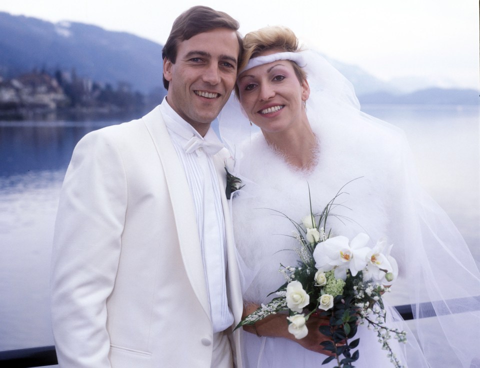 a bride and groom pose for a picture in front of a lake