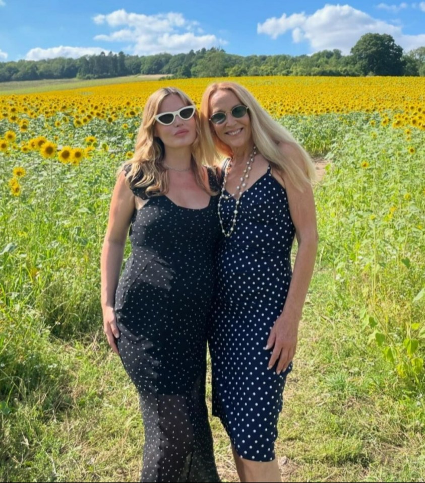 two women standing in front of a field of sunflowers