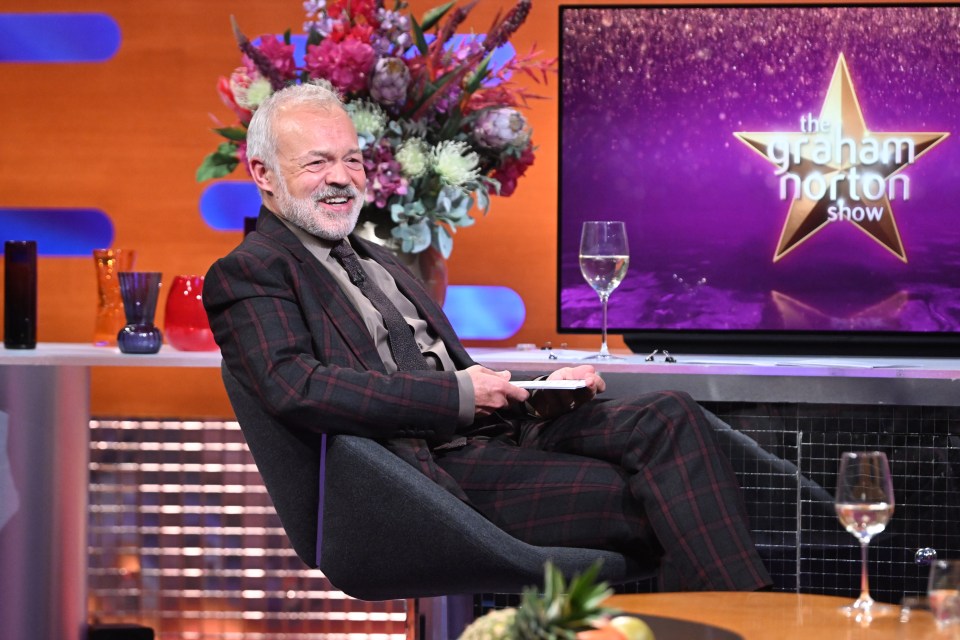 a man sits in front of a sign that says the graham norton show