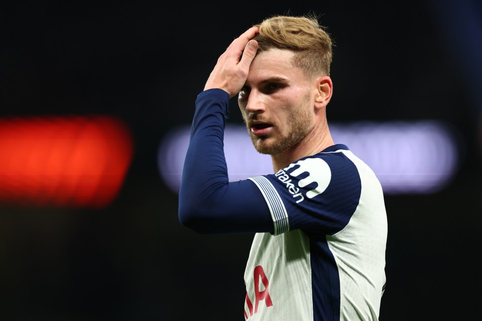 a man wearing a tottenham jersey holds his hand to his forehead