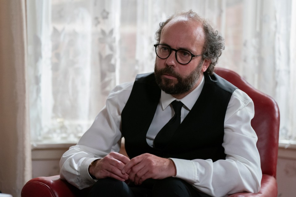 a man with glasses and a beard sits in a chair