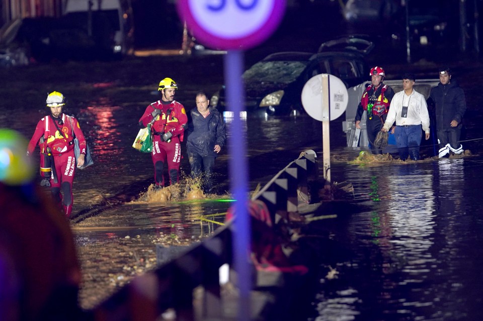 a group of people walking through a flooded street with a sign that says 30