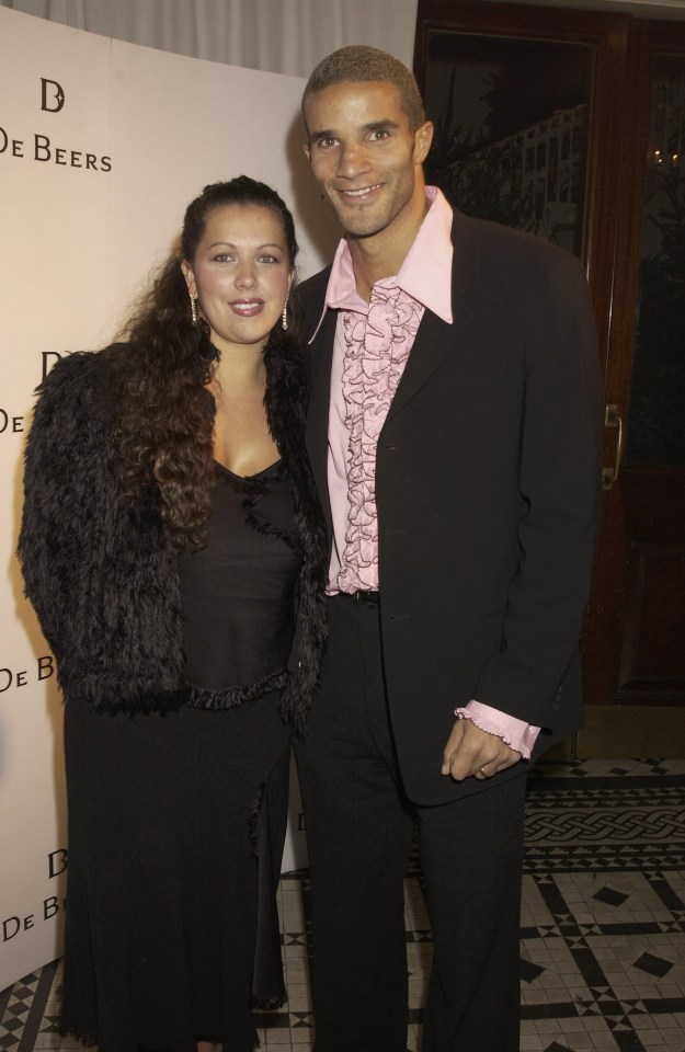 a man and woman pose in front of a wall that says de beers