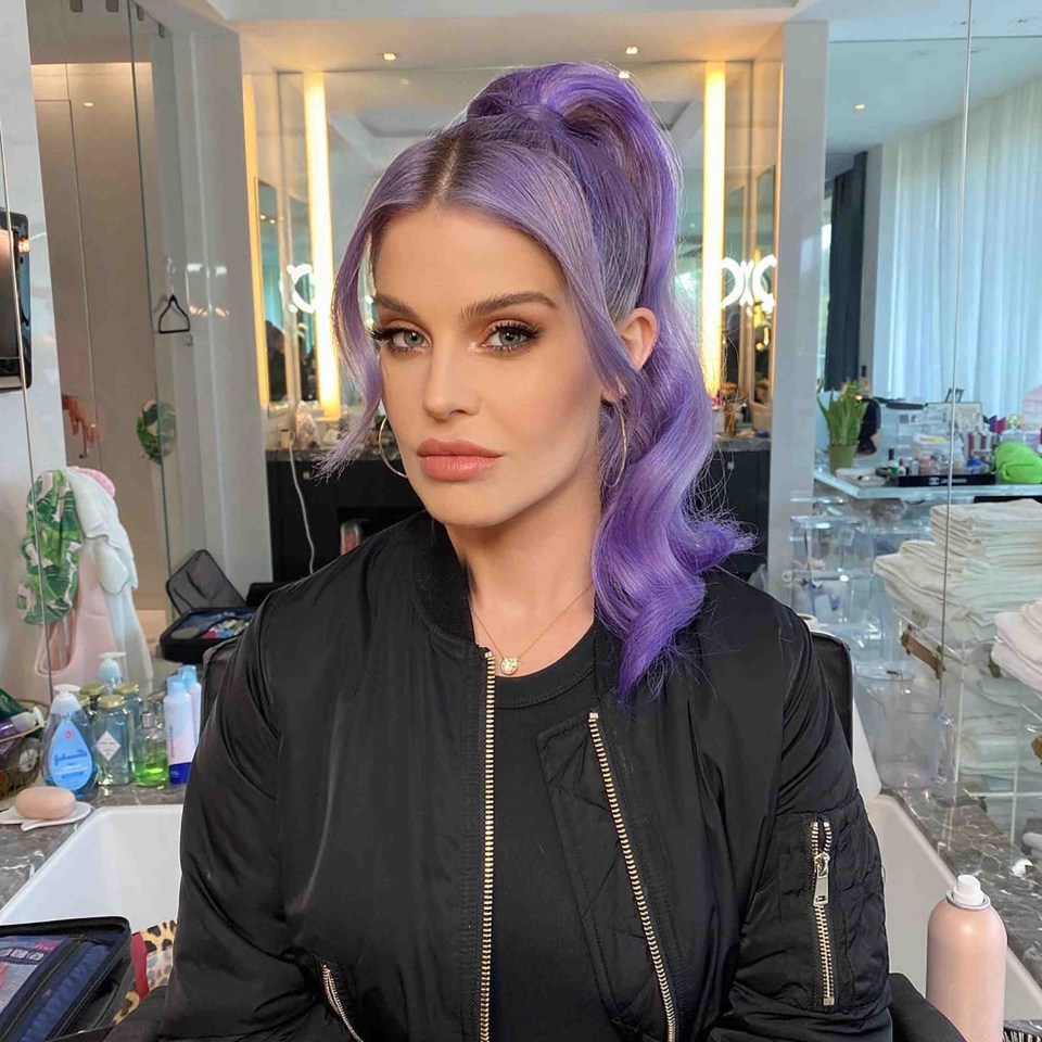 a woman with purple hair is wearing a black jacket