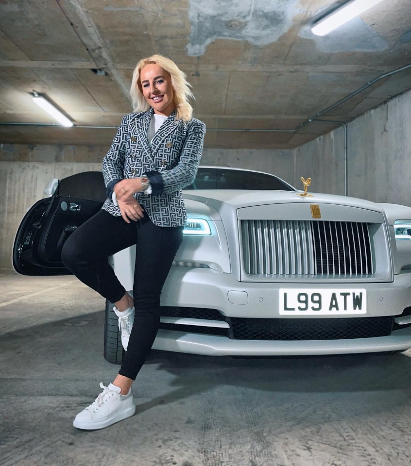 a woman leans on a white car with a license plate that says l99 atw