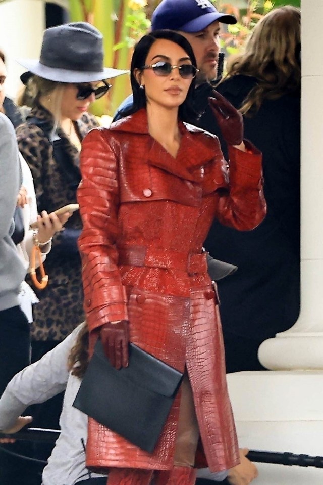 a woman wearing a red coat and gloves holds a black clutch