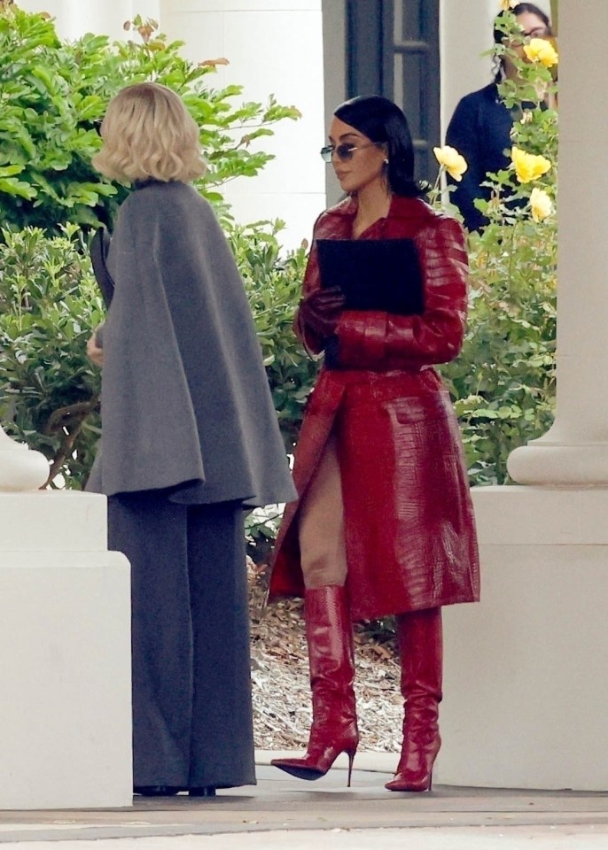 a woman in a red coat and red boots stands next to another woman