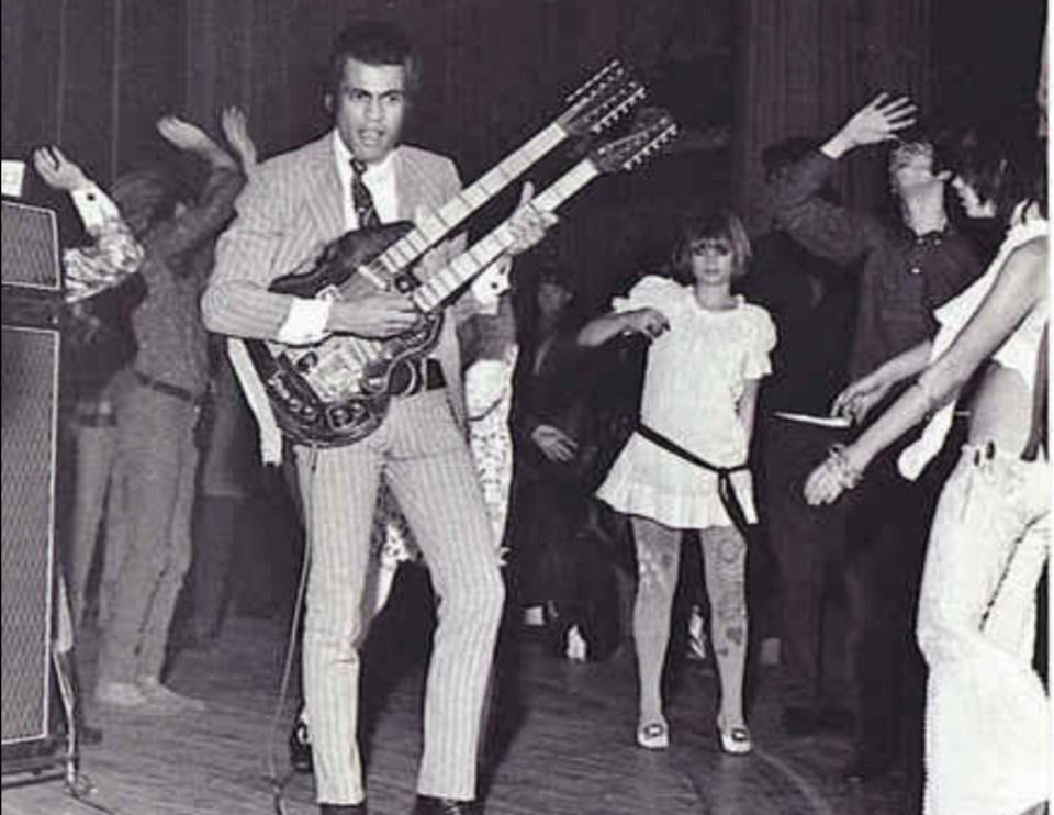 a man is playing a double neck guitar in front of a crowd of people .