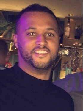 a man with a beard is smiling for a picture in a bar .