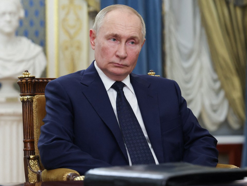 a man in a suit and tie sits in a chair