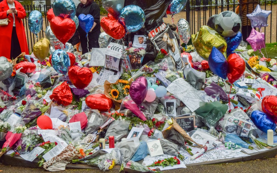 a pile of flowers and balloons with a sign that says " i love you "