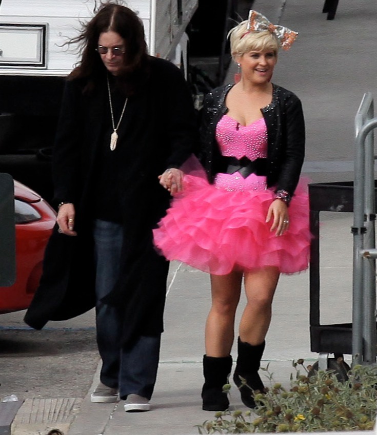 a woman in a pink dress is walking with a man in a black coat