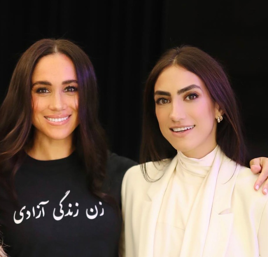 three women are posing for a picture and one of them is wearing a shirt with arabic writing on it