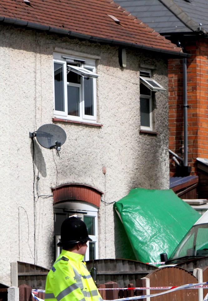 a police officer in front of a house with a green tarp on the roof