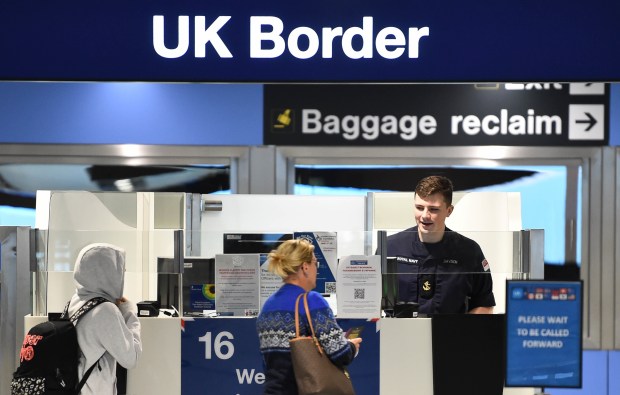 a woman stands in front of a uk border baggage reclaim counter