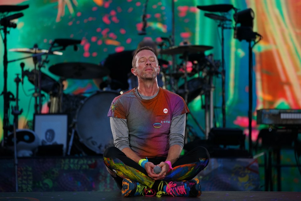 a man sits in a lotus position on a stage with his eyes closed