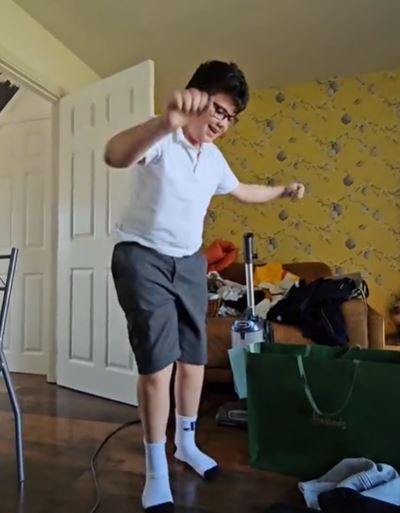 a young boy in a white shirt and shorts is dancing in a living room .