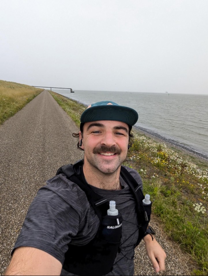 a man wearing a hat and a salomon vest smiles for the camera