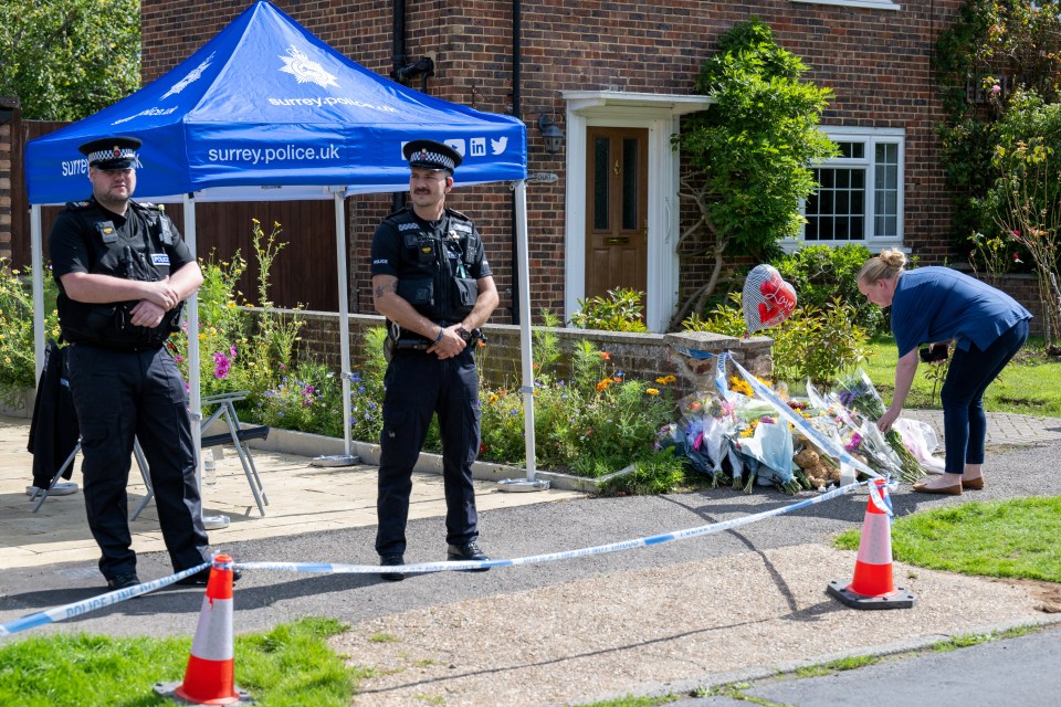 two police officers stand in front of a blue tent that says surrey police.uk