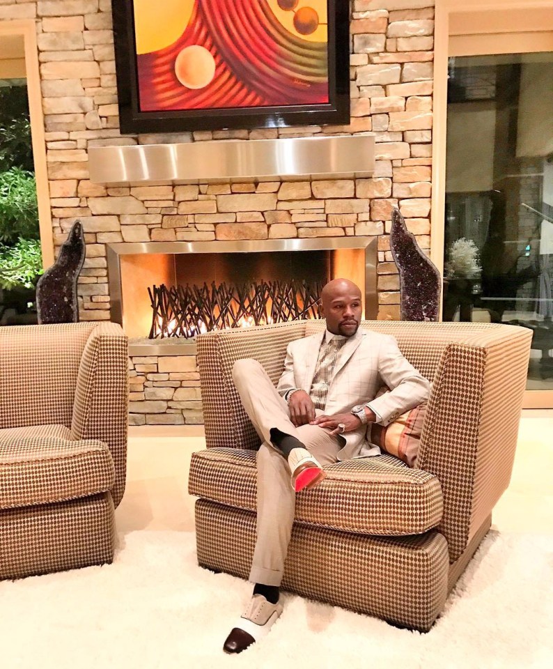 a man in a suit sits in a chair in front of a fireplace