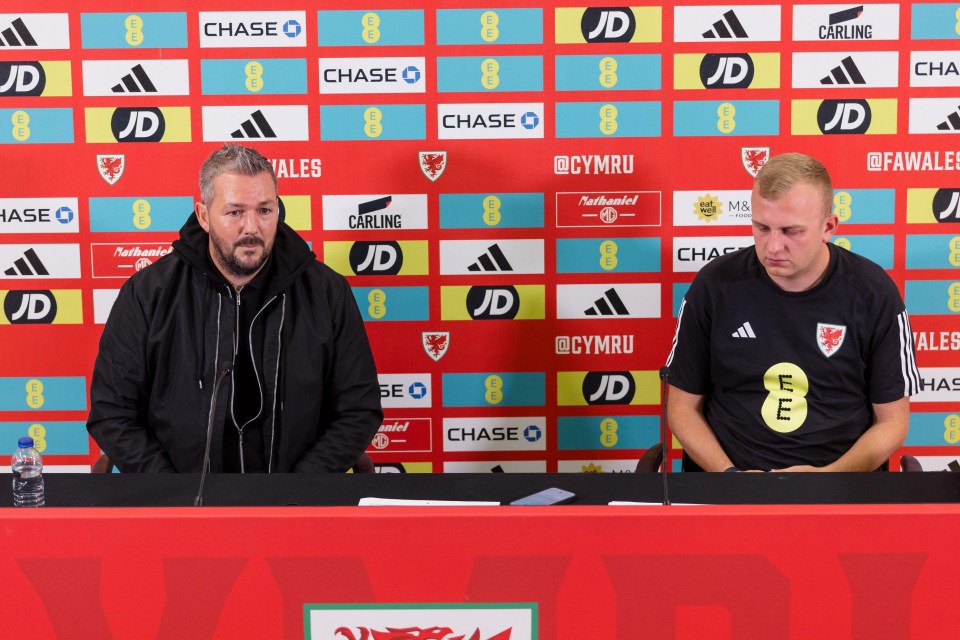 two men are sitting at a table in front of a wall that says chase and jd