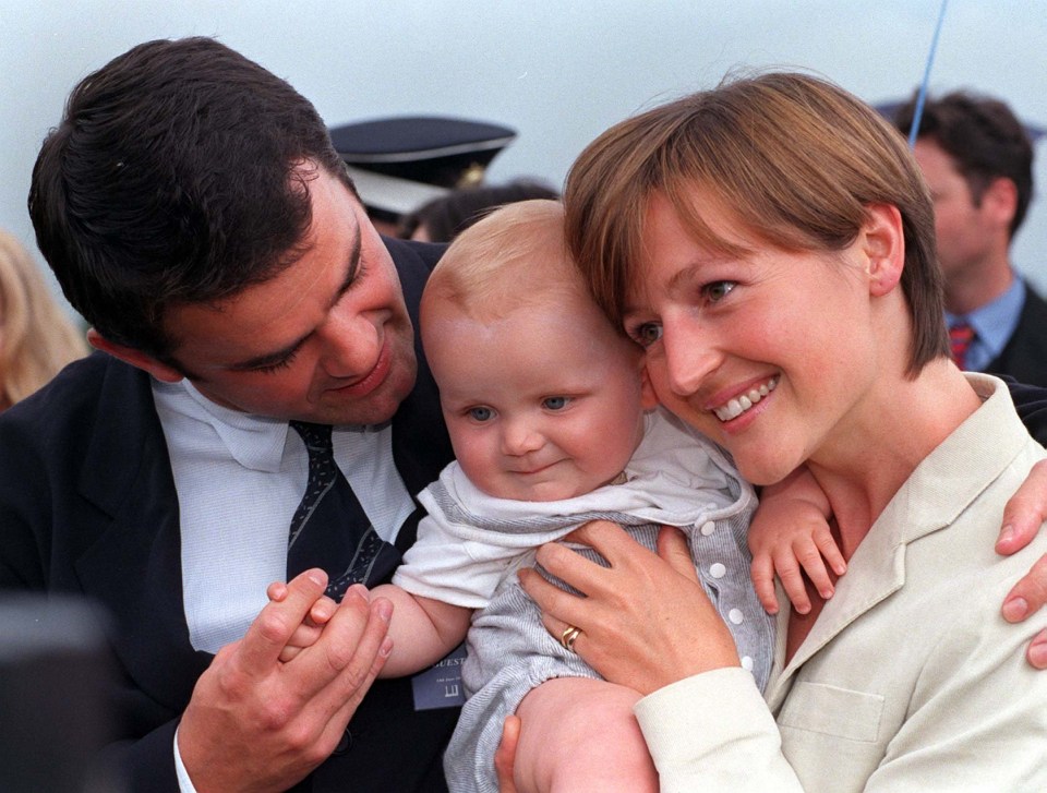 a man and woman are holding a baby and the woman has a ring on her finger