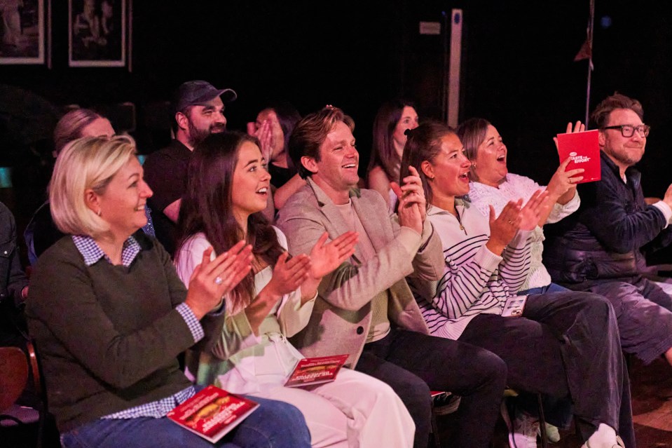 a group of people sitting in a dark room applauding