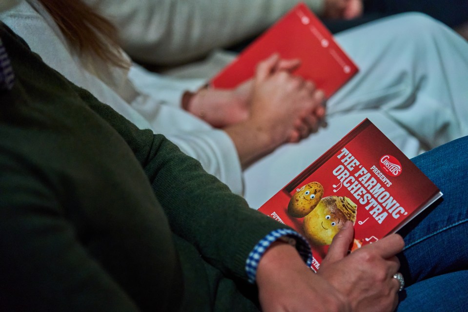 a person holding a book titled the farmonic orchestra