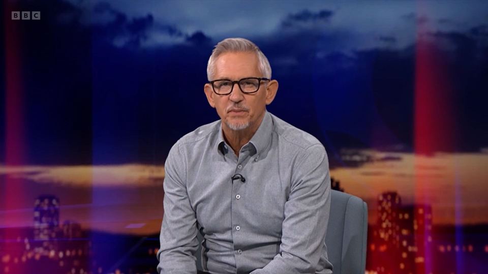 a man sitting in front of a bbc logo