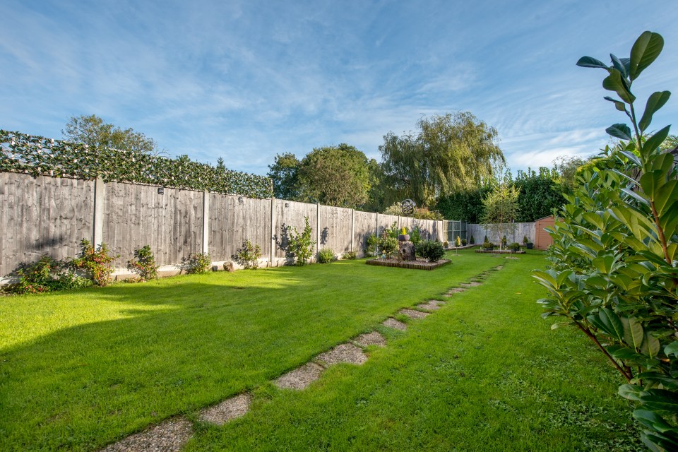 a backyard with a wooden fence and a lush green lawn