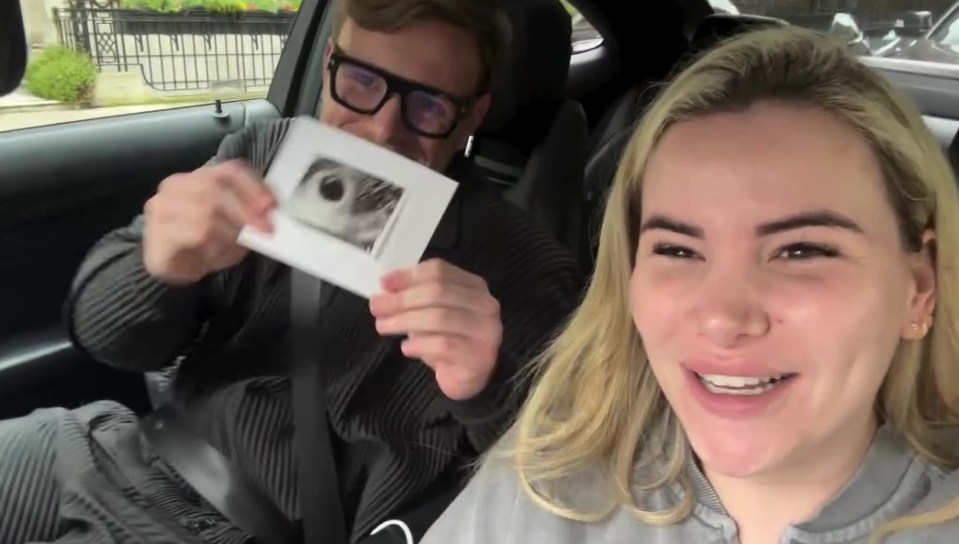 a man and a woman in a car holding a picture of a baby